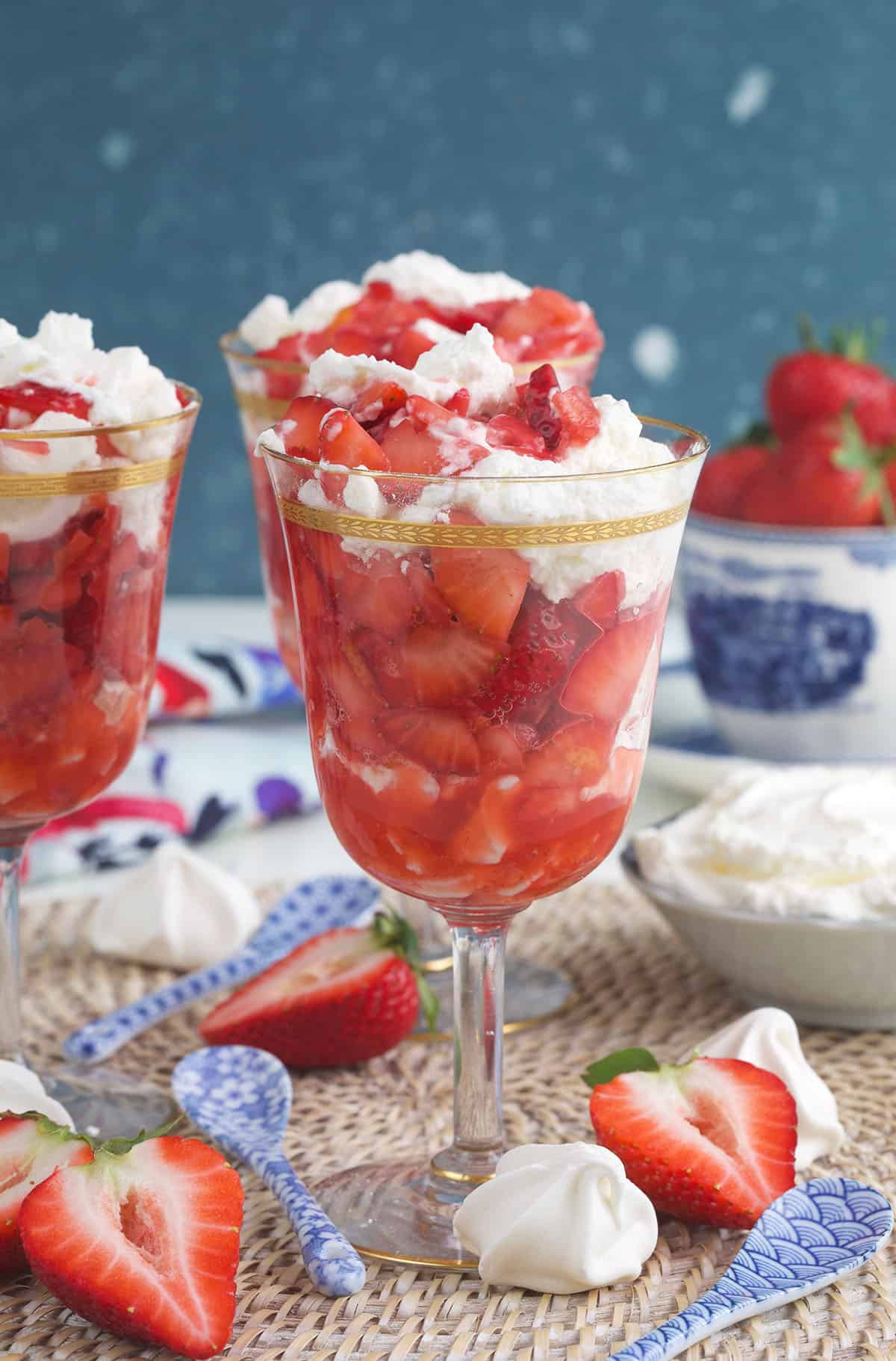 Strawberries and meringue cookies are placed around a single serving of eton mess.