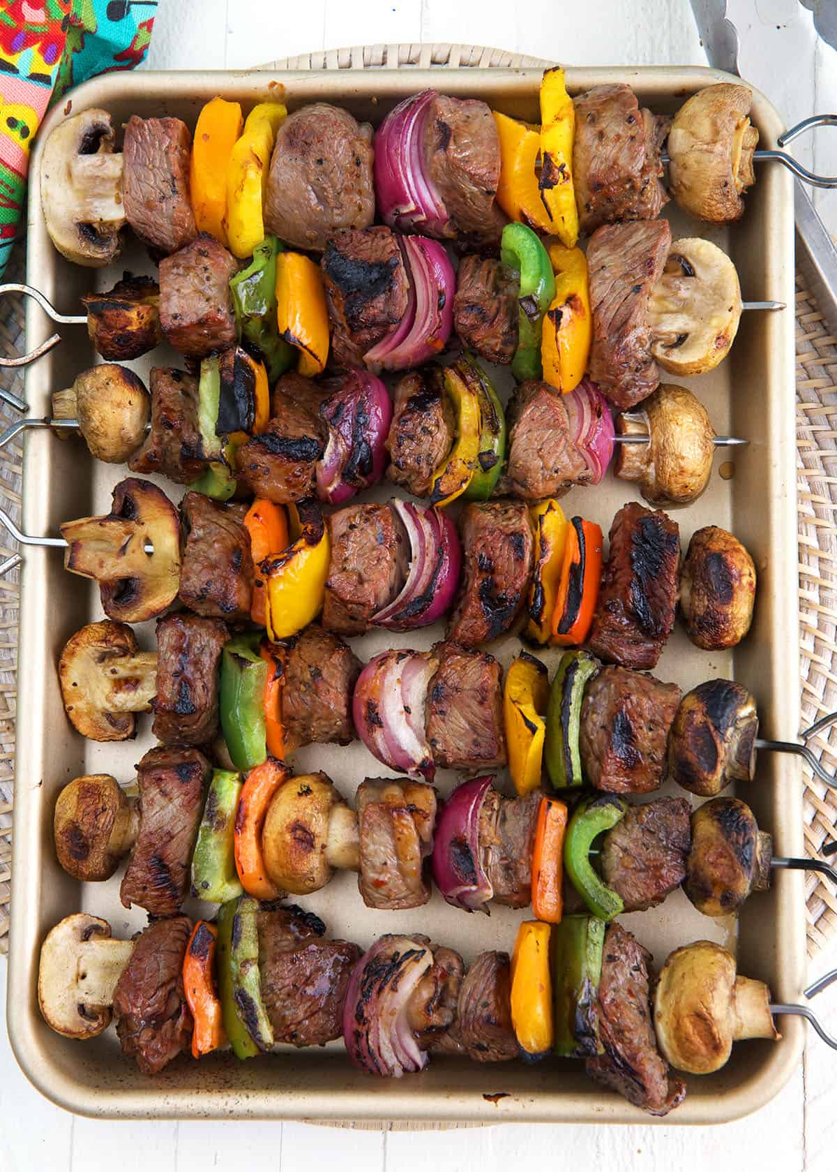 A baking sheet is topped with several cooked steak shish kabobs. 