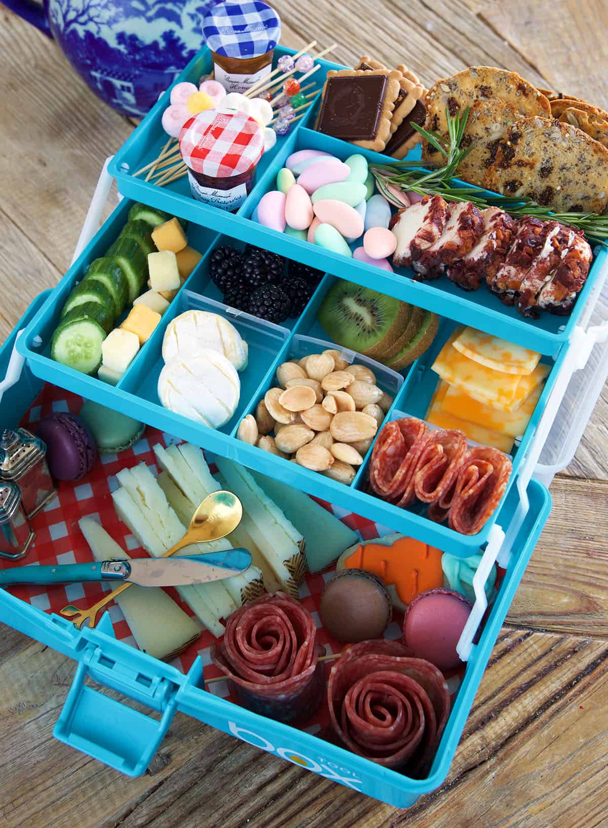 A tiered blue tackle box is filled with all different snacks.