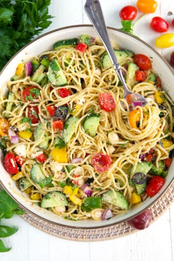 A fork is twirling a bite of spaghetti salad.