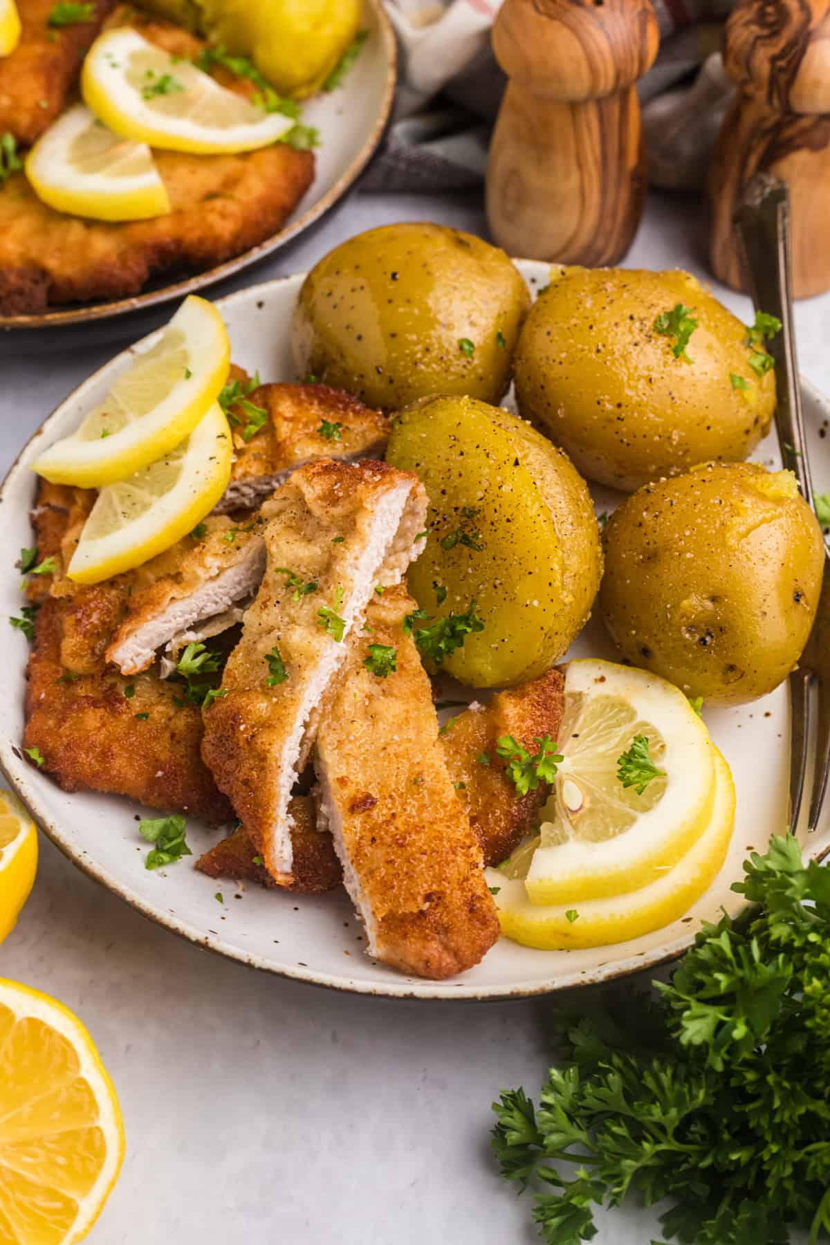 Sliced wiener schnitzel is plated with boiled yukon gold potatoes. 