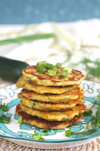 A stack of zucchini fritters are placed on a plate.