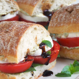 Balsamic glaze is drizzle in the middle of a halved caprese sandwich.