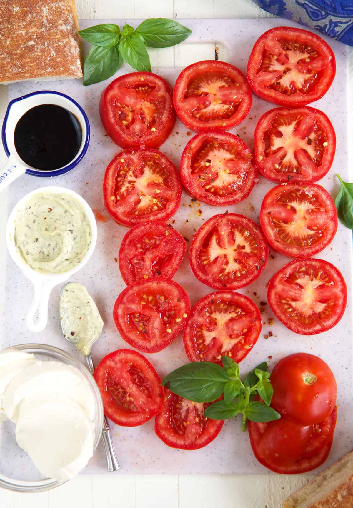 Slices of fresh tomatoes are placed next to balsamic glaze and seasonings. 
