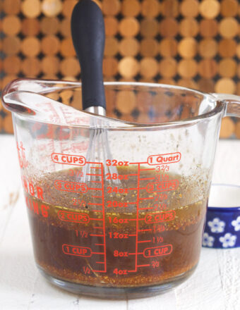 A whisk is stirring ingredients together in a measuring glass.