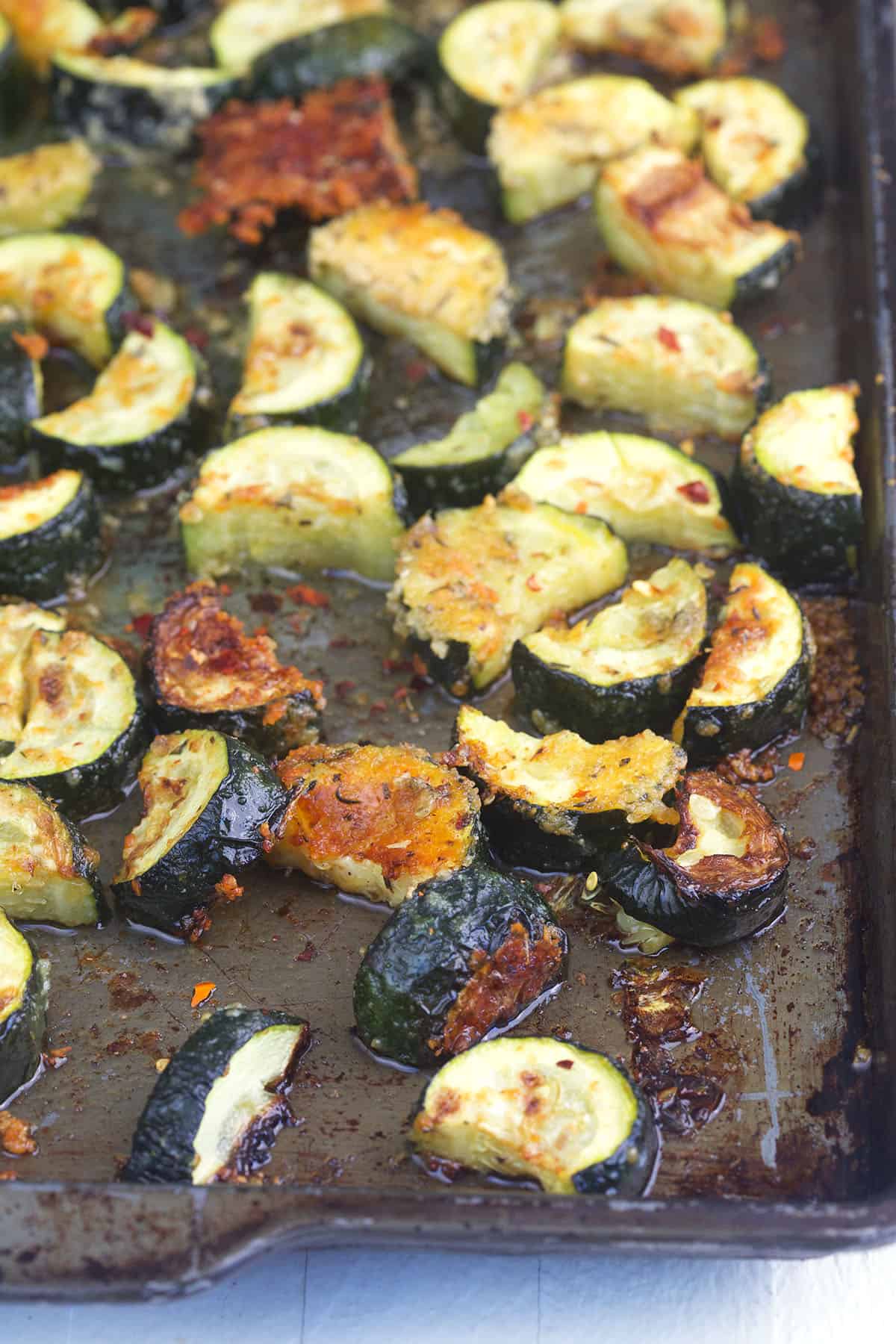 Roasted zucchini is spread on a baking sheet.