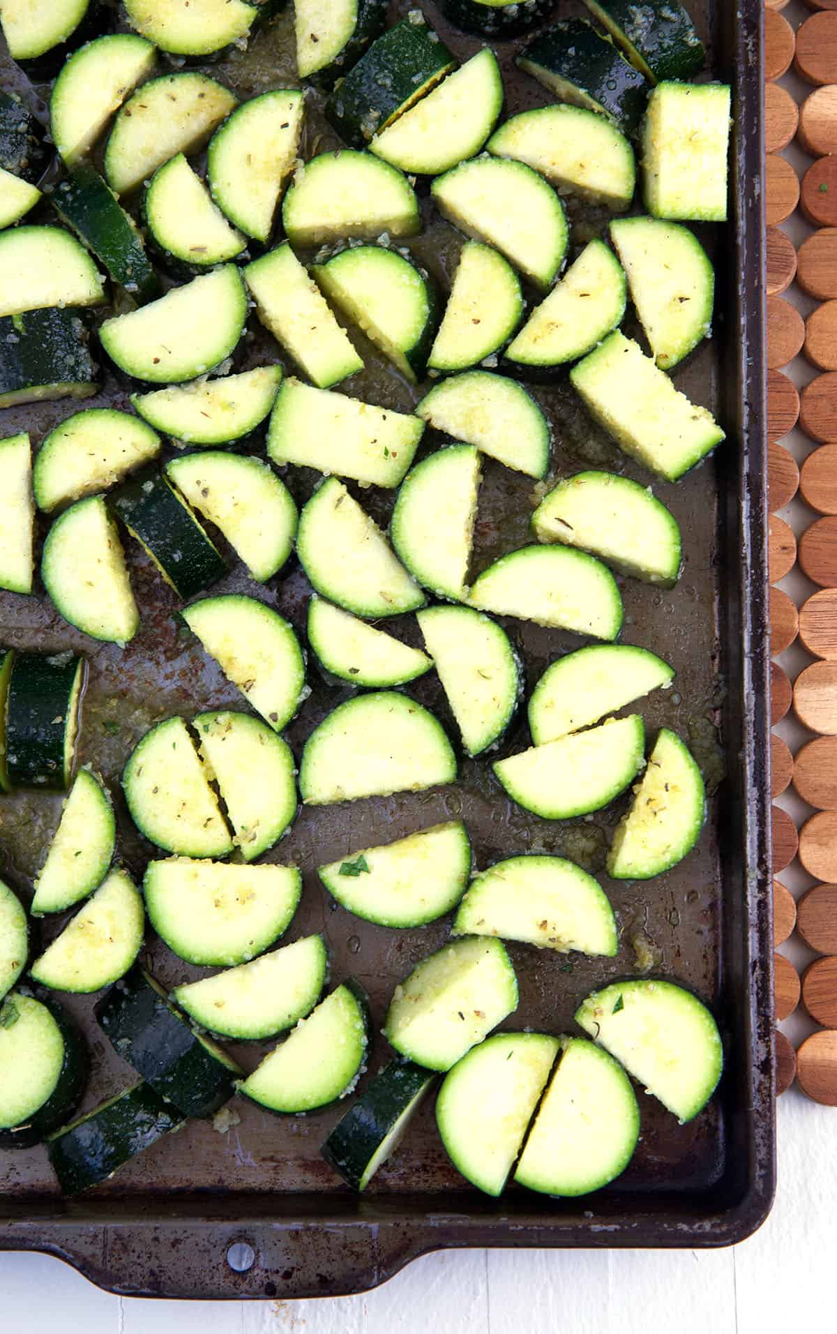 Chopped fresh zucchini is spread out on a baking sheet.