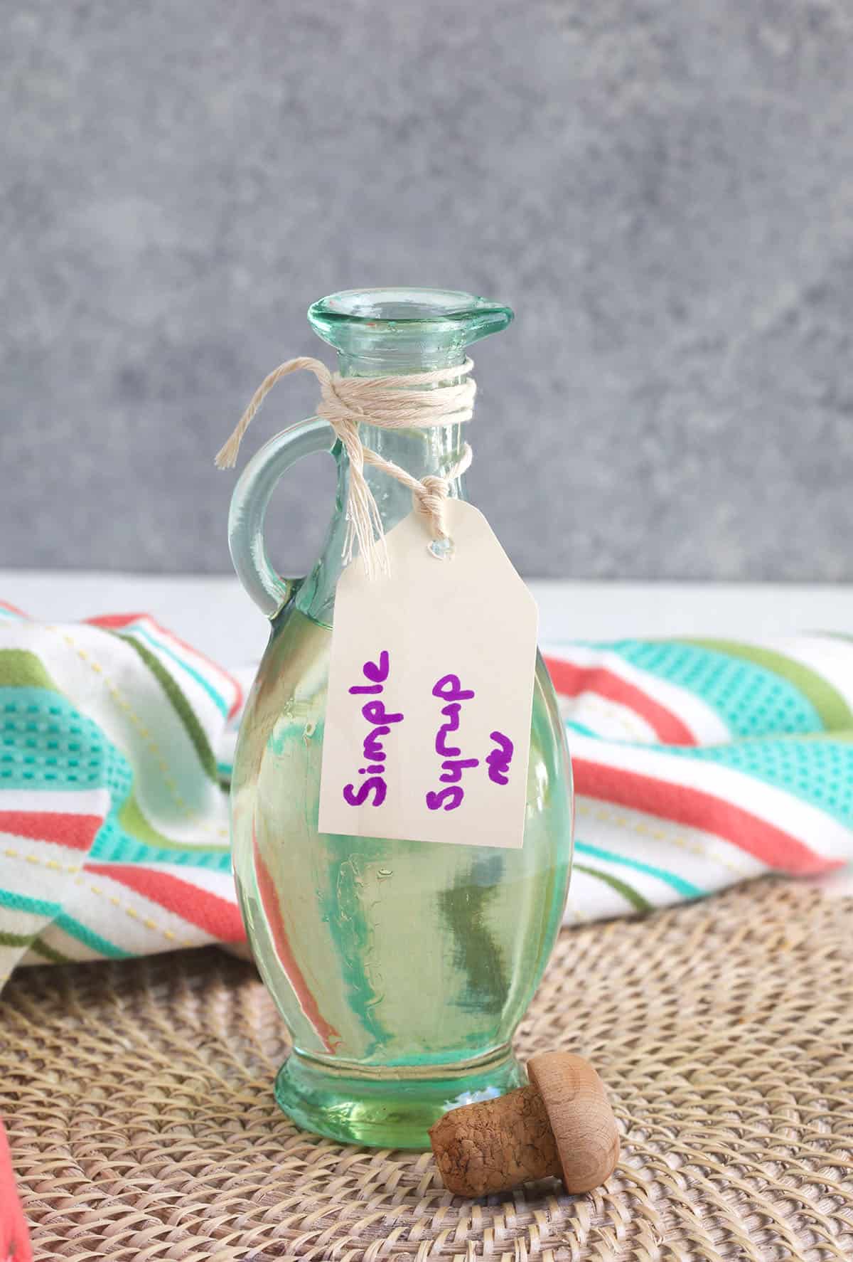 Glass bottle with a label marked Simple Syrup in purple marker.