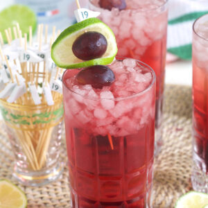 Two glasses of transfusion cocktail are garnished with grapes and limes.