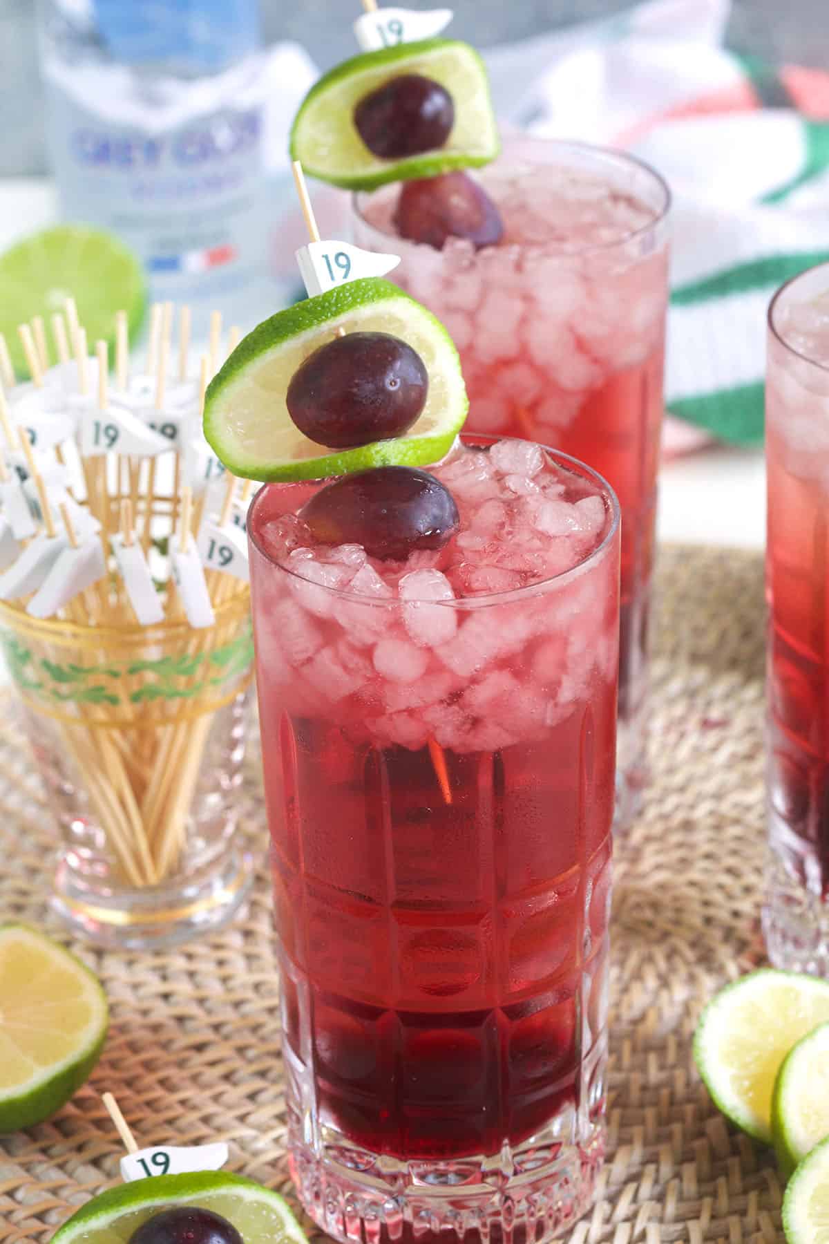 Two glasses of transfusion cocktail are garnished with grapes and limes. 