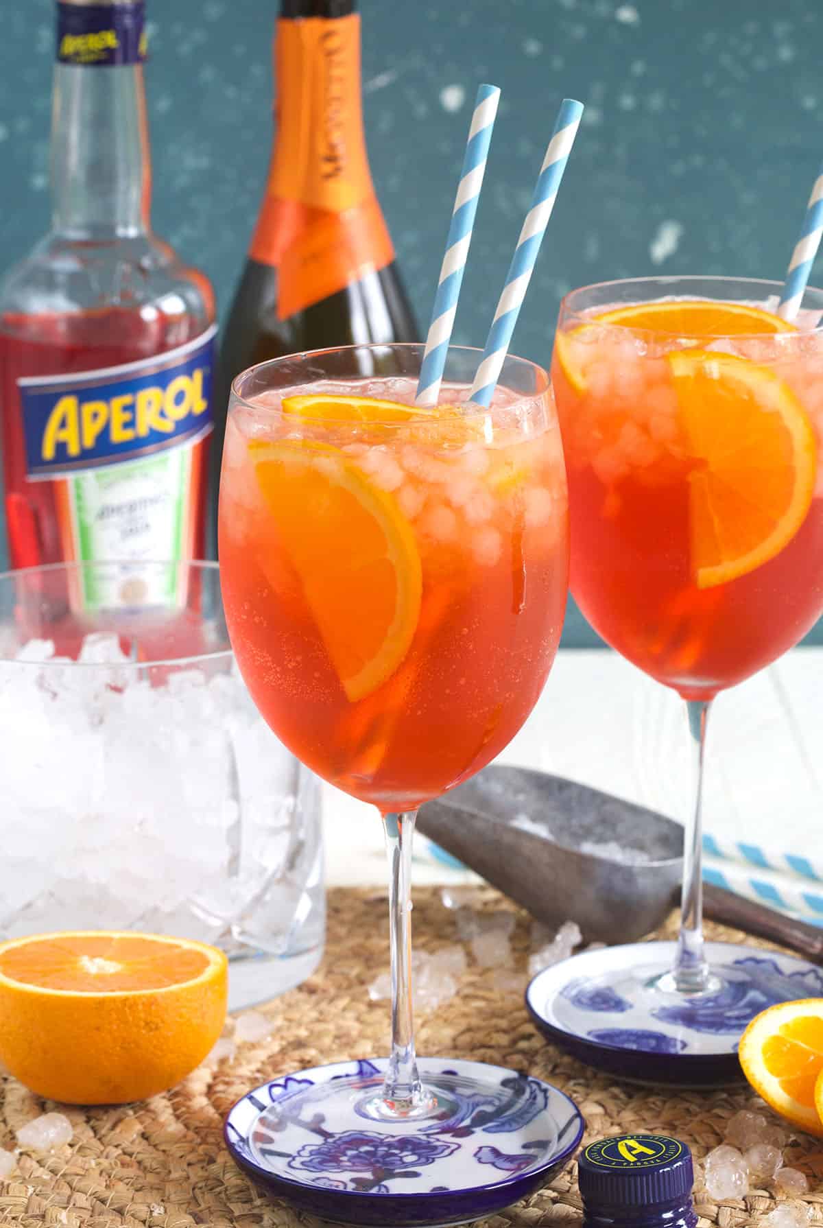 An aperol spritz is garnished with an orange slice and two straws. 