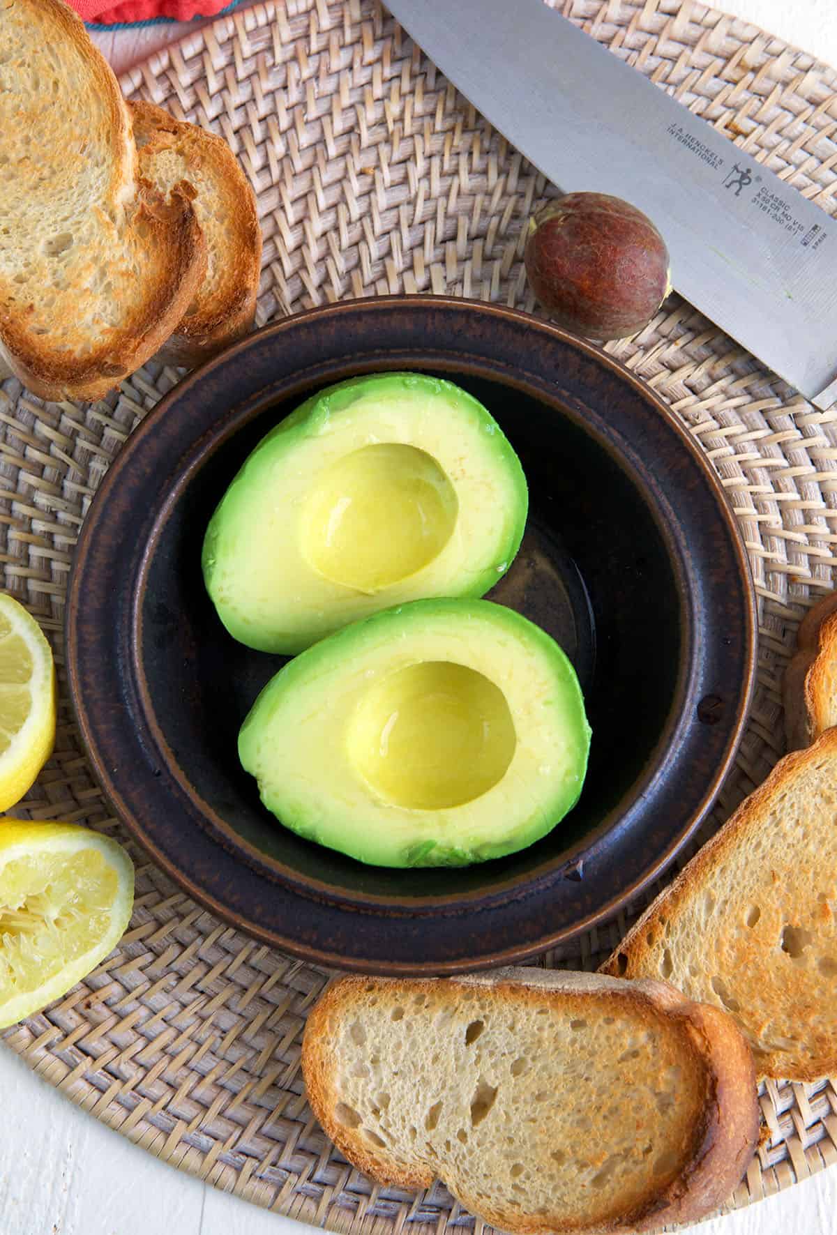 A halved avocado is placed in a small bowl. 
