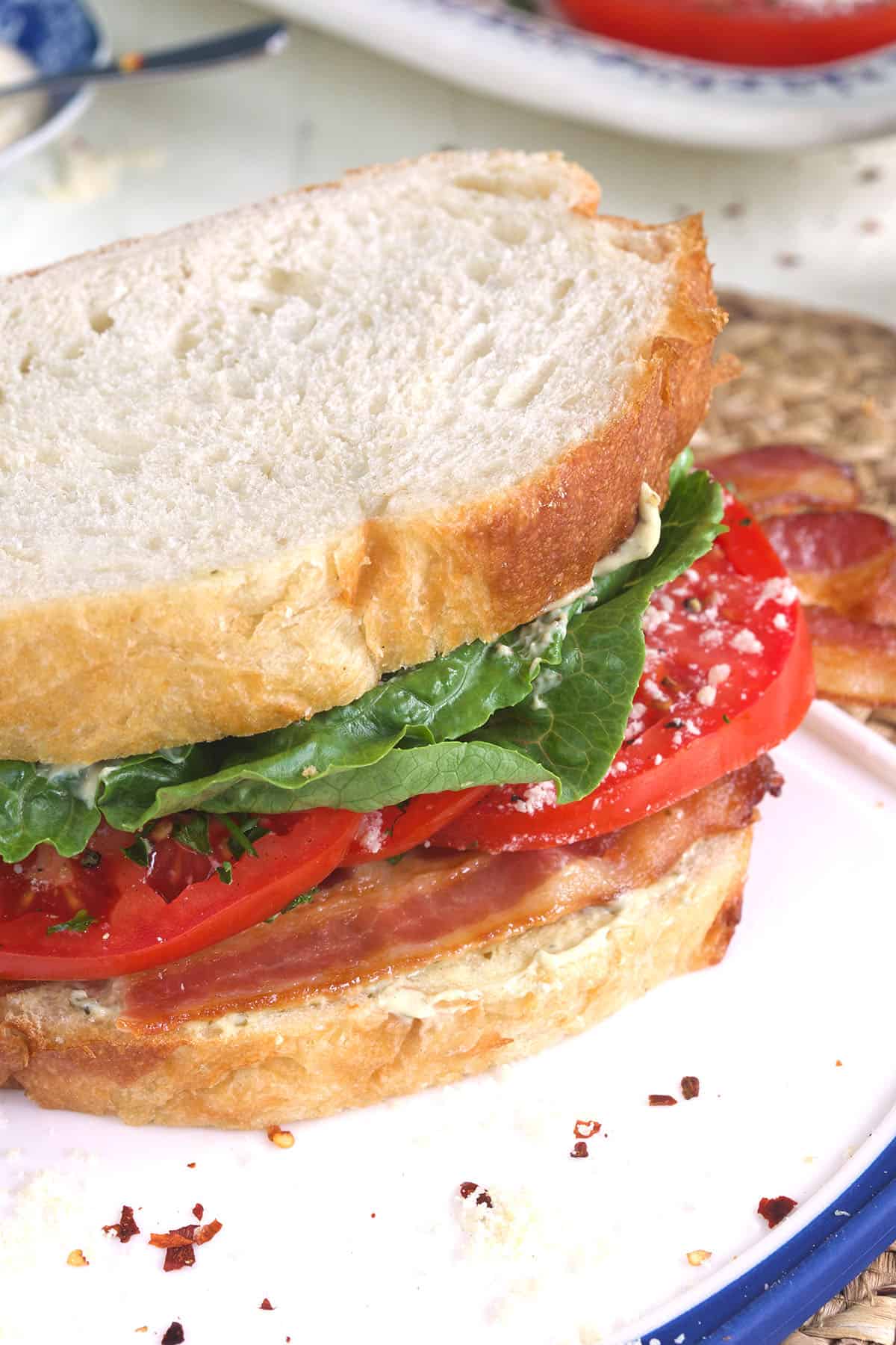 BLT sandwich on white bread positioned on a cutting board.