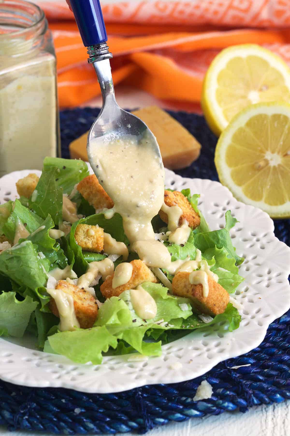 Caesar dressing is being drizzled over a salad. 