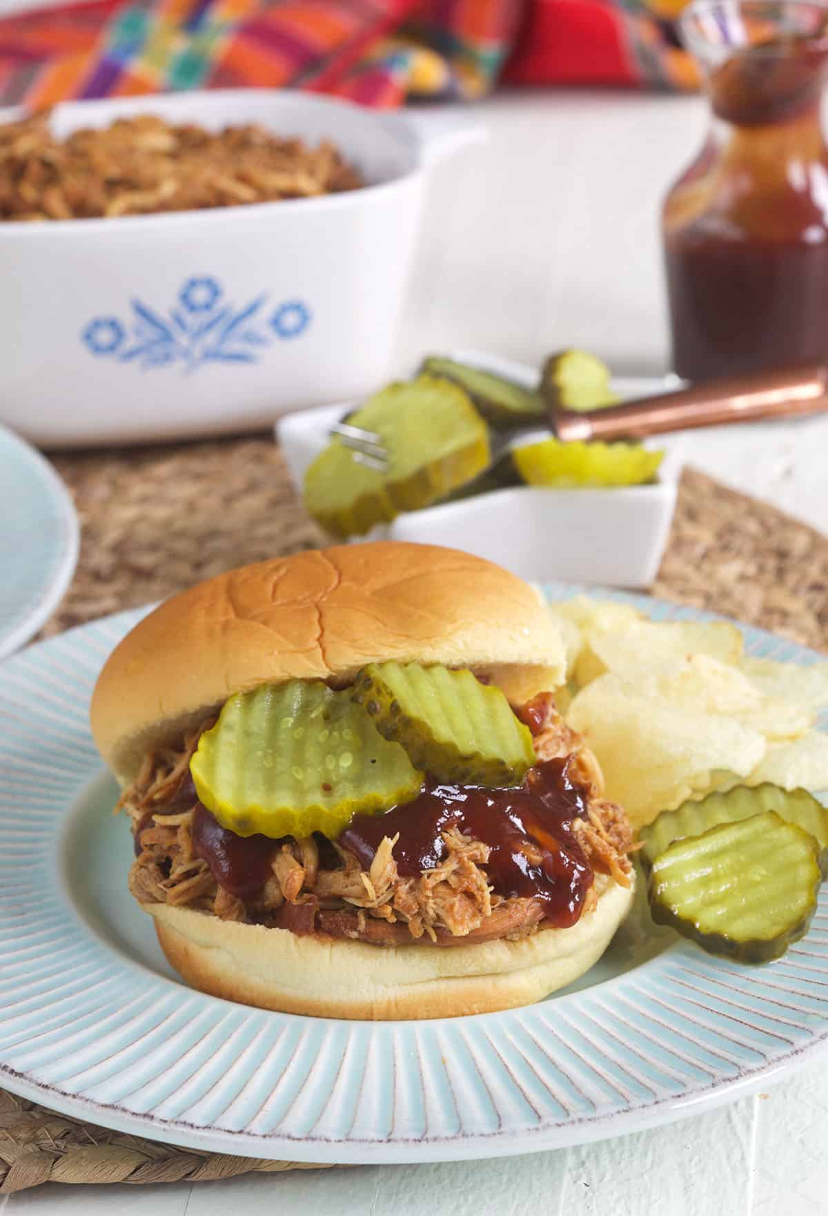 Pickles are placed on a bbq sandwich. 
