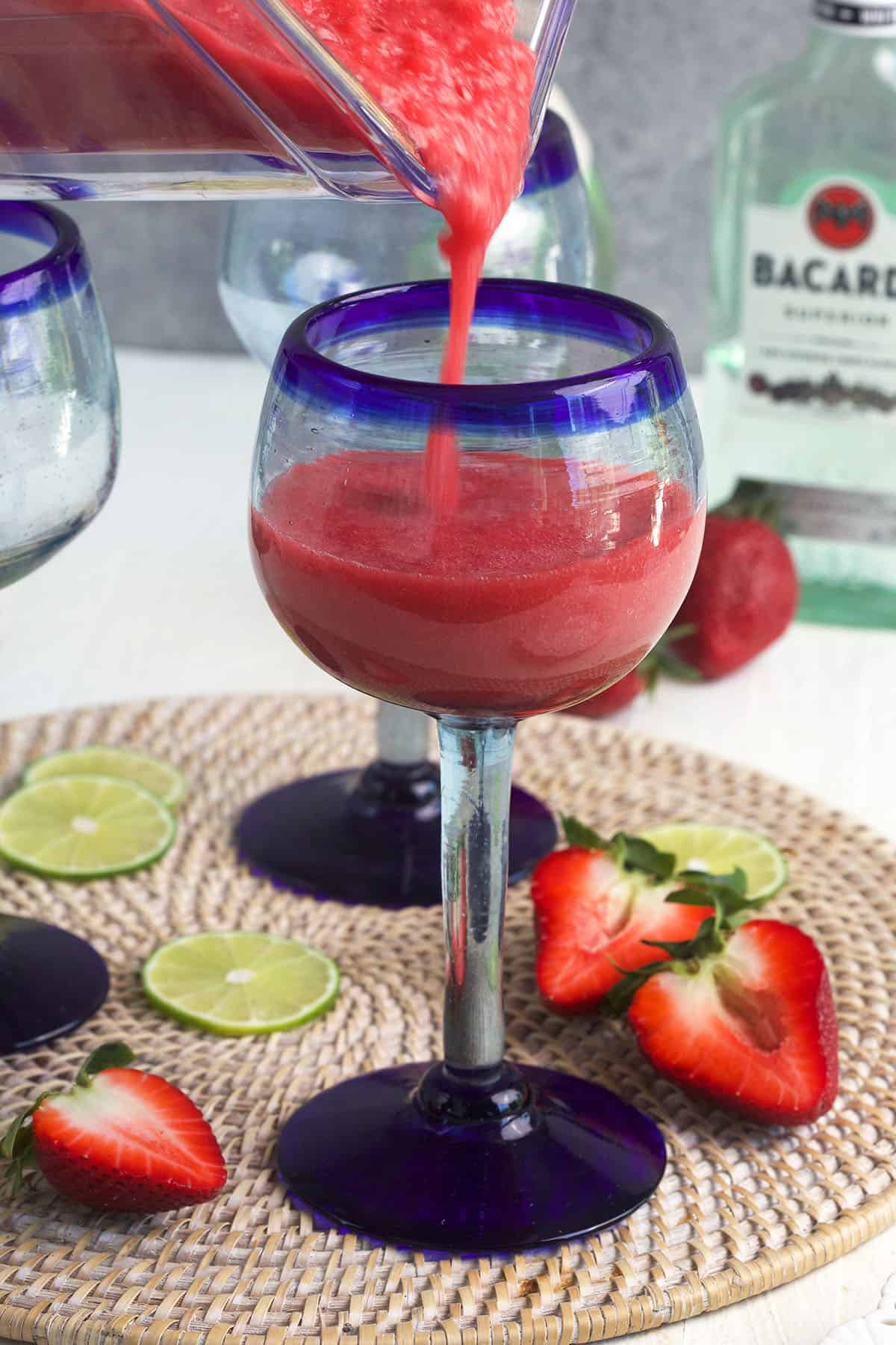 Frozen strawberry daiquiri is being poured into a glass. 