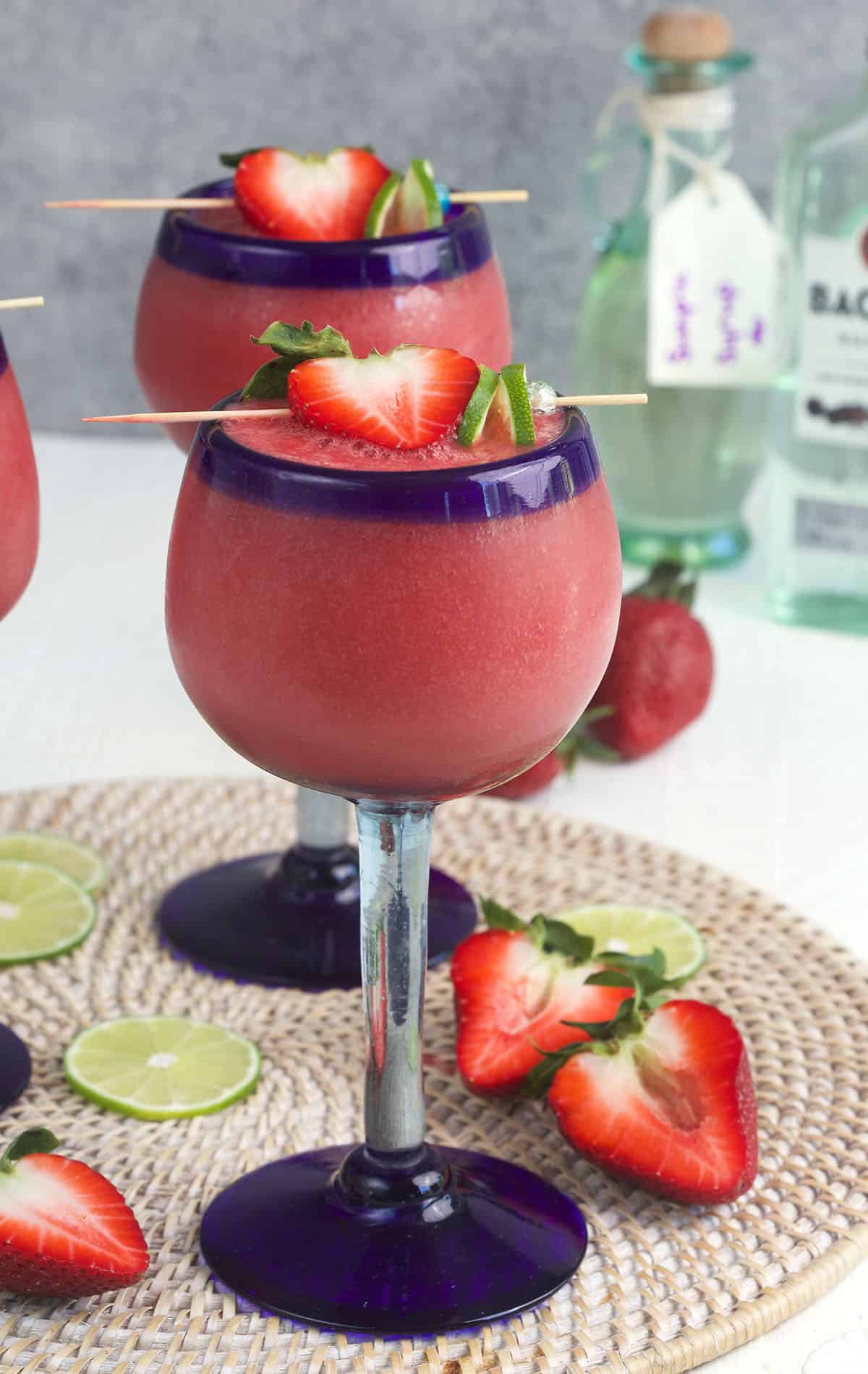 Two glasses of daiquiris are placed on a round place mat. 