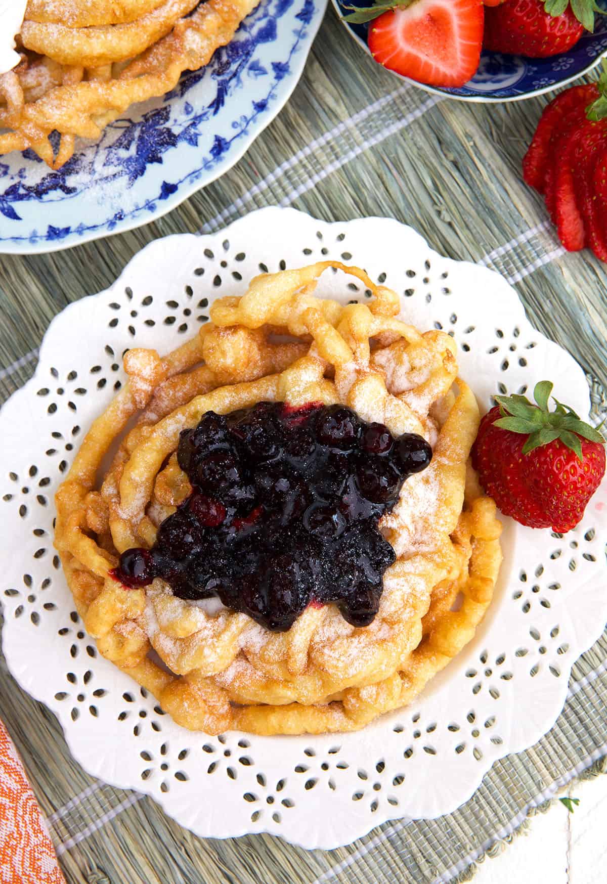 Blueberry jam is placed on top of a cooked funnel cake. 