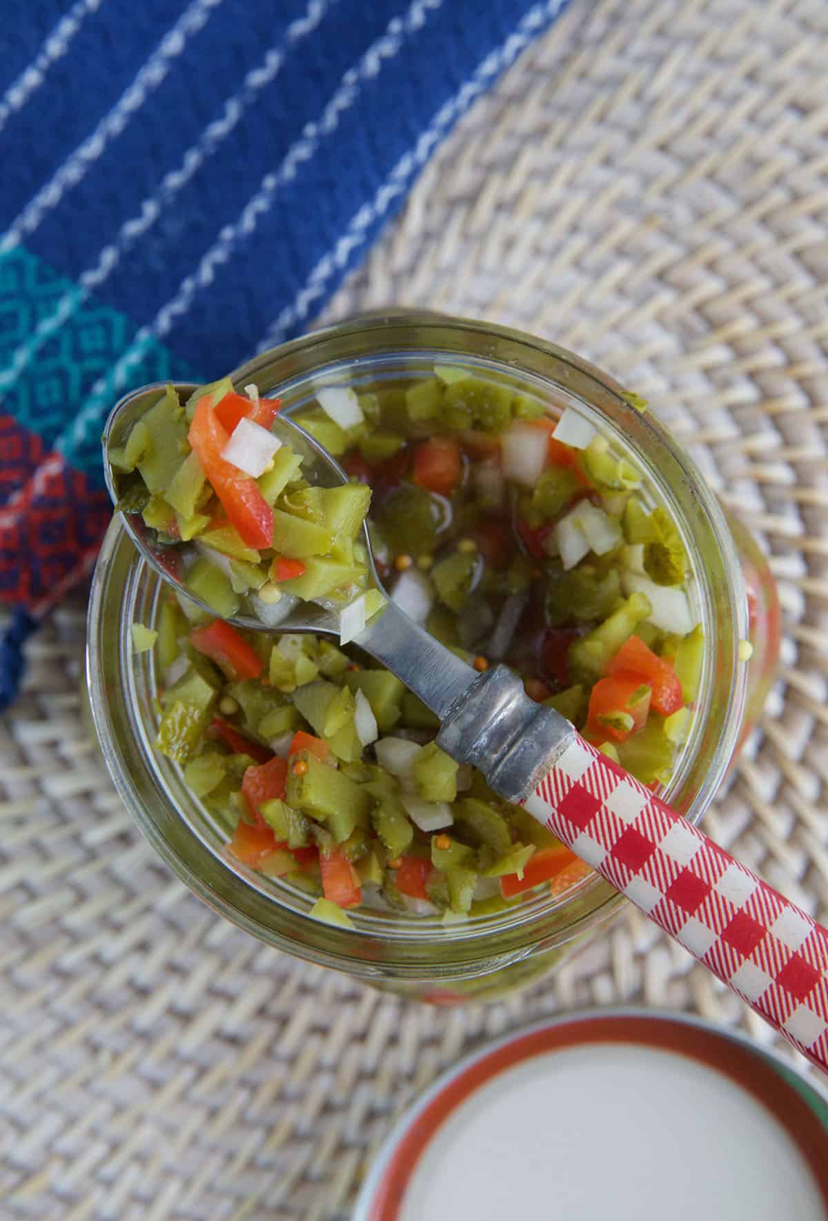A spoon is placed on top of a jar of relish. 