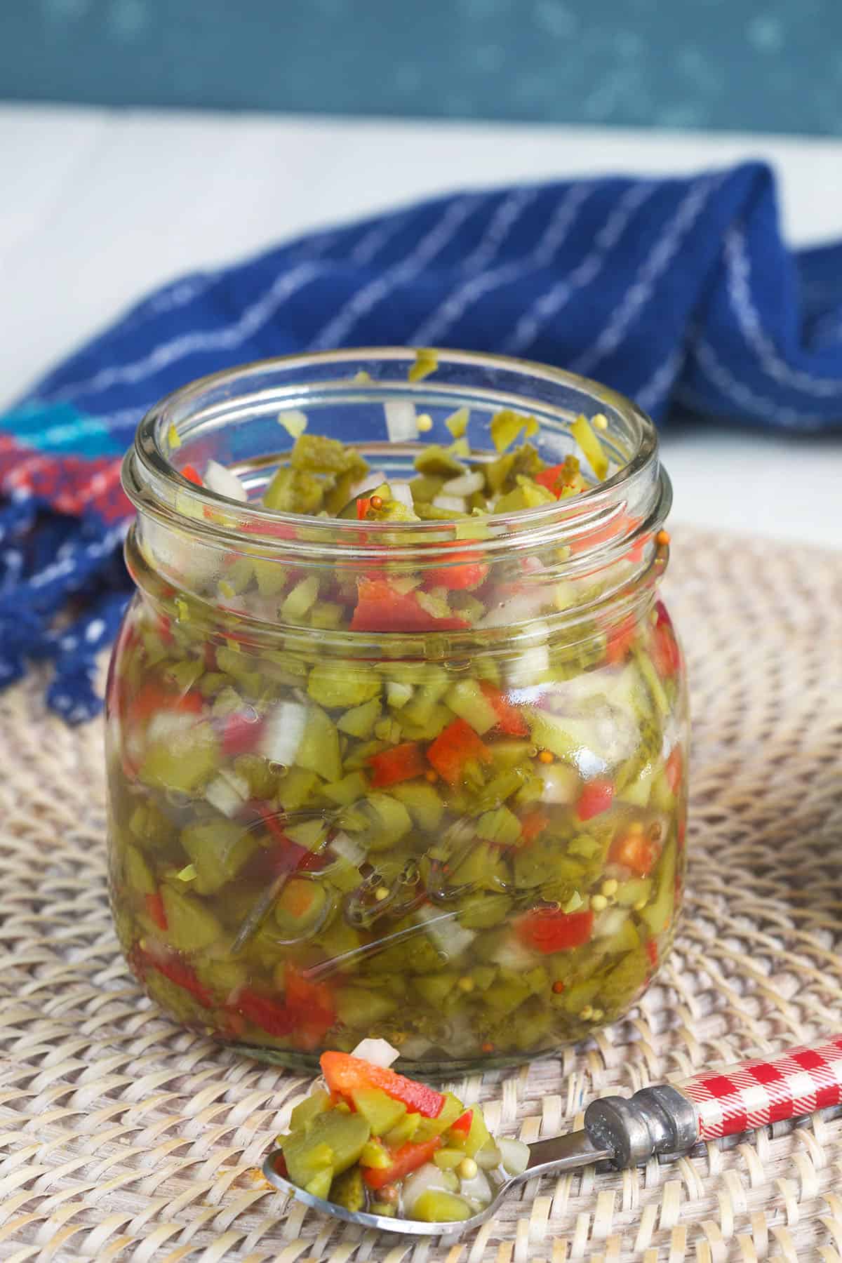 A spoon is placed next to a full jar of relish. 