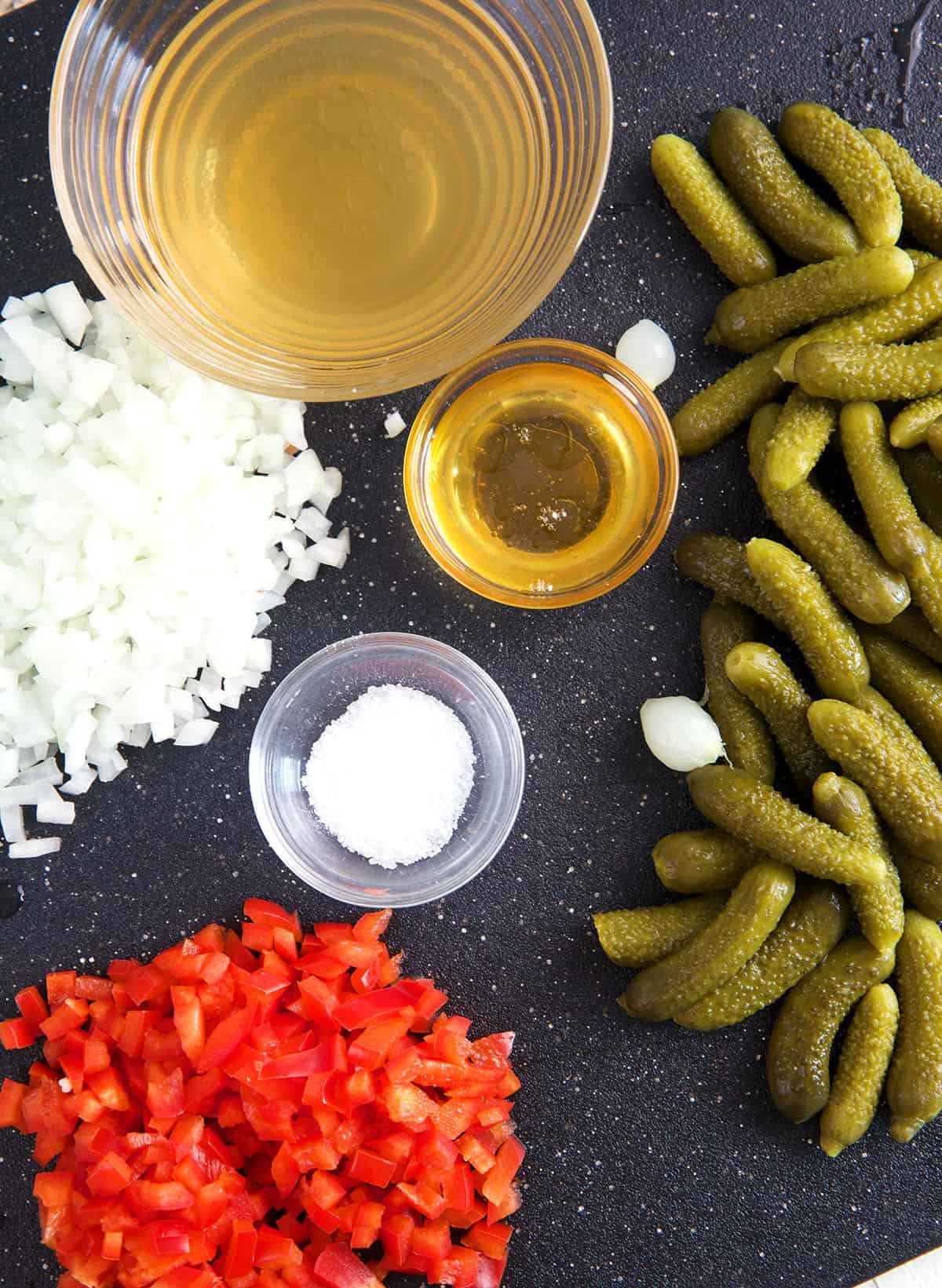 The ingredients for pickle relish are placed on a dark surface. 