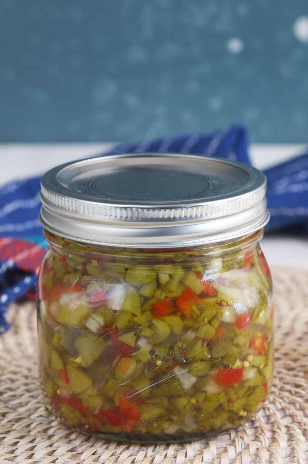 A jar of pickle relish is placed on a placemat. 