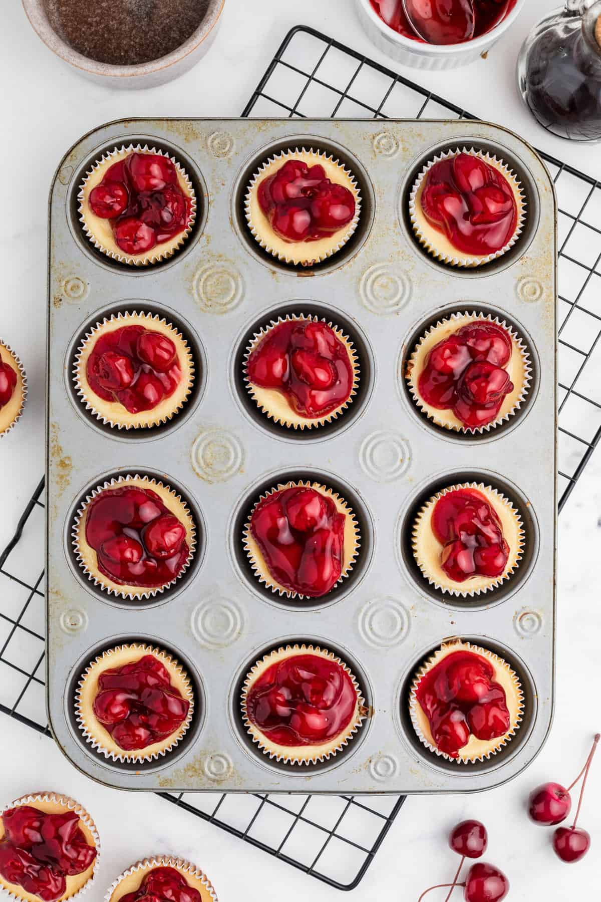 Mini cherry cheesecakes are presented in a cupcake pan. 