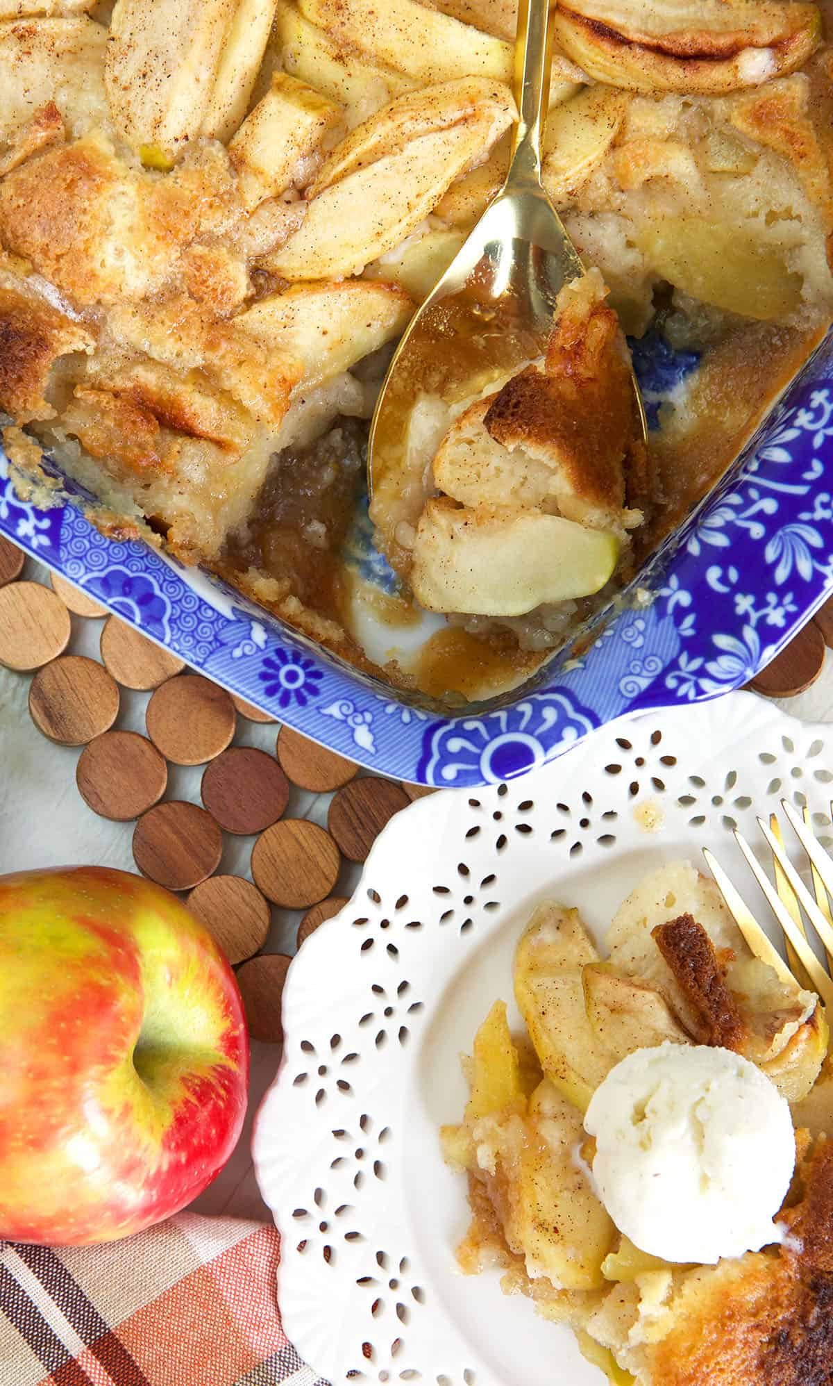A single serving of apple cobbler is placed next to a whole cobbler. 