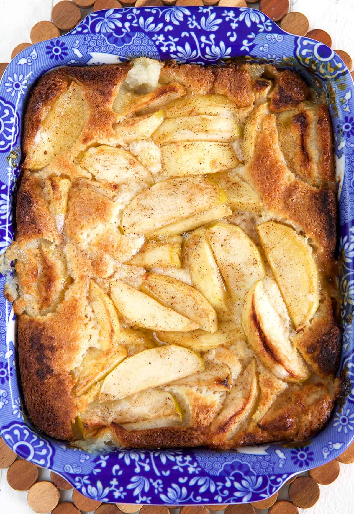 A baked apple cobbler is presented in a blue baking dish. 