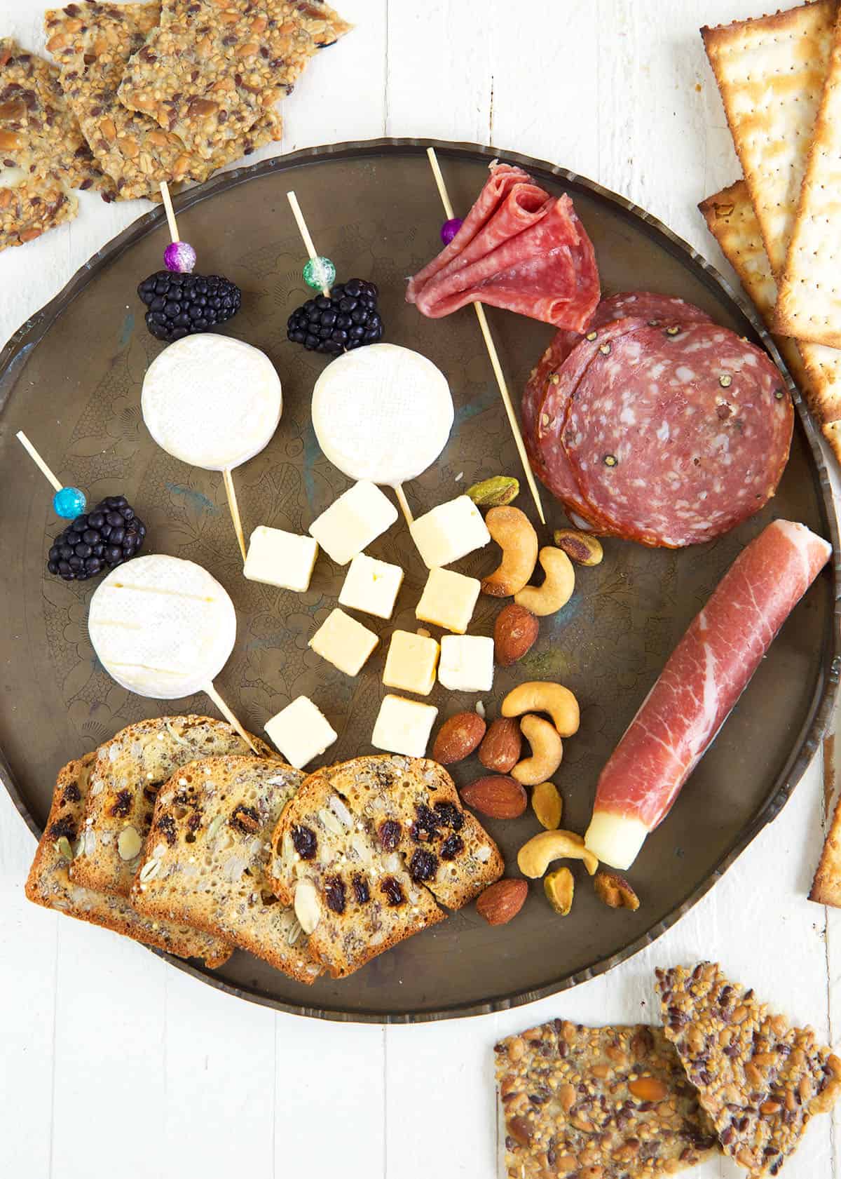 Ingredients for charcuterie cups are placed on a round plate. 