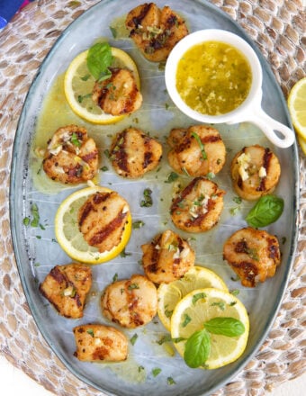 A batch of grilled scallops are served. on a round plate.