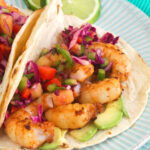 Shrimp tacos are plated with lime slices.