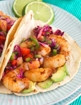 Shrimp tacos are plated with lime slices.