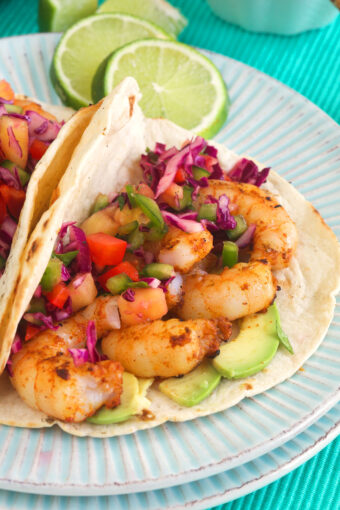 Shrimp tacos are plated with lime slices.
