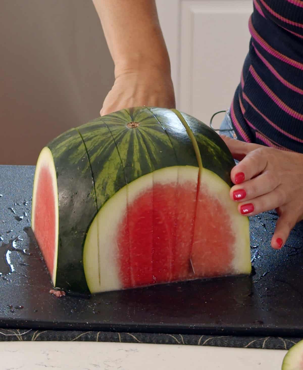 A watermelon is being sliced on a cutting board. 