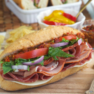 An Italian hoagie is placed on a wooden cutting board.