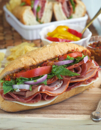 An Italian hoagie is placed on a wooden cutting board.