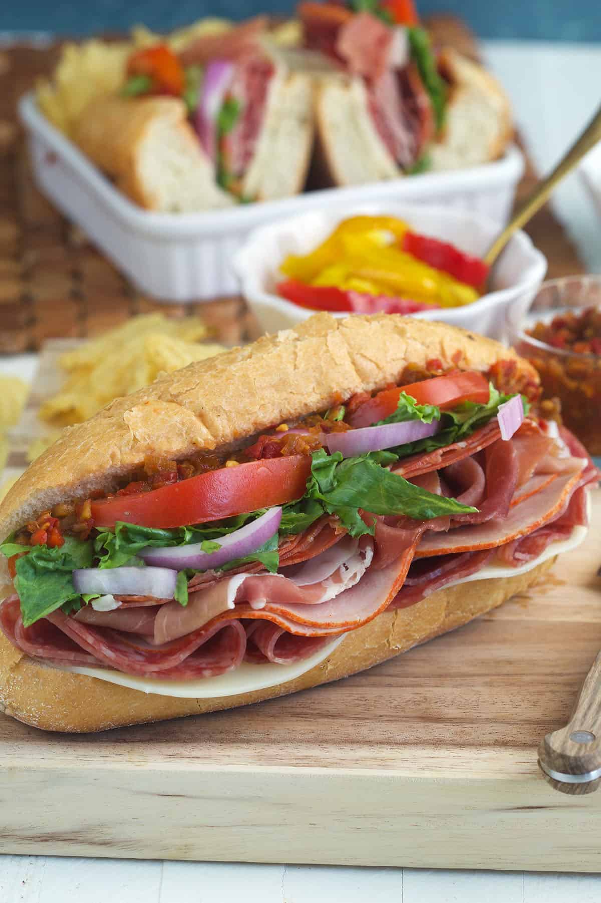 An Italian hoagie is placed on a wooden cutting board. 