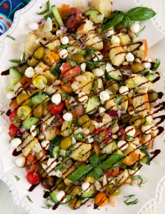 Balsamic reduction is drizzled all over panzanella salad.