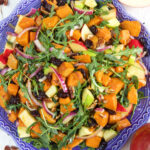 A large blue serving plate is topped with sweet potato salad.