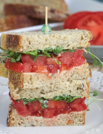 A tomato sandwich has been cut in half and stacked.