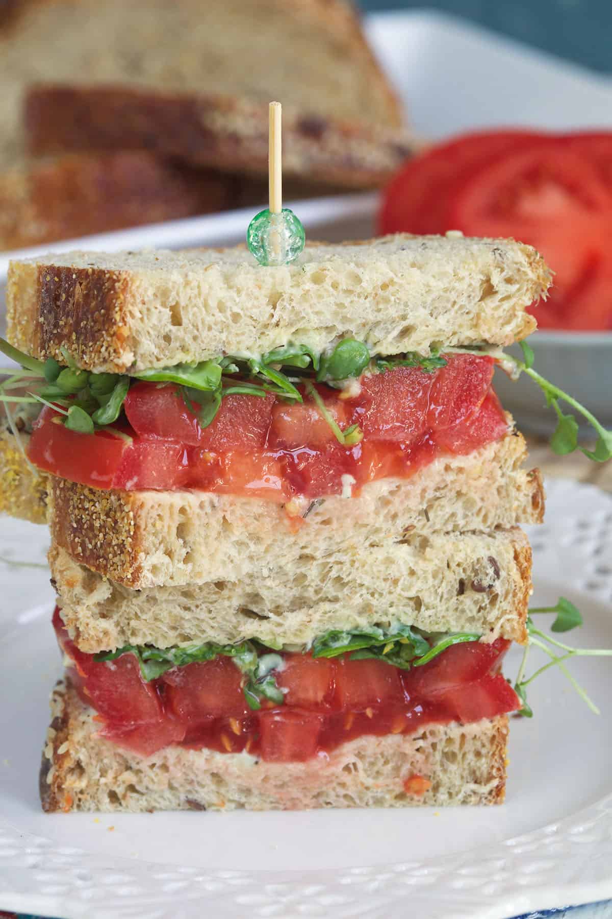A tomato sandwich has been cut in half and stacked. 