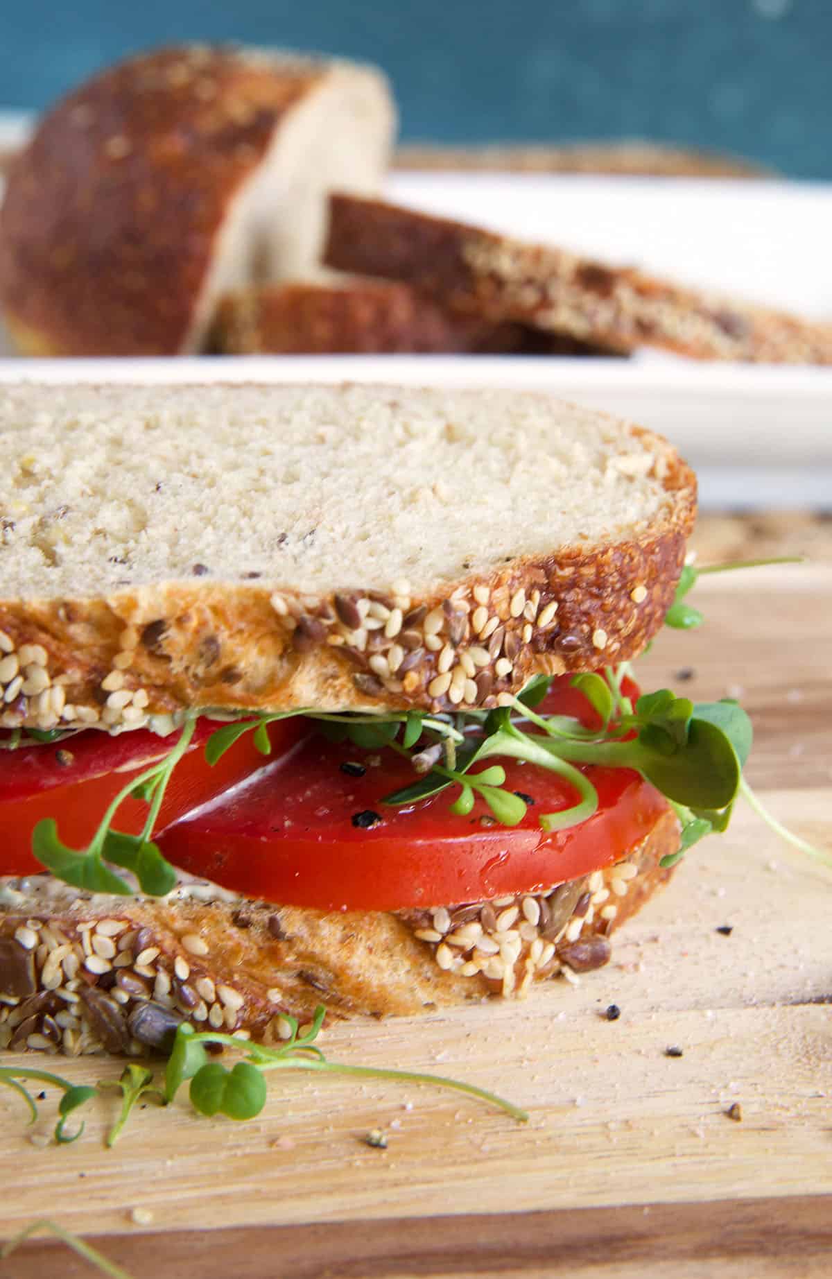 A tomato sandwich is placed on a wooden surface.