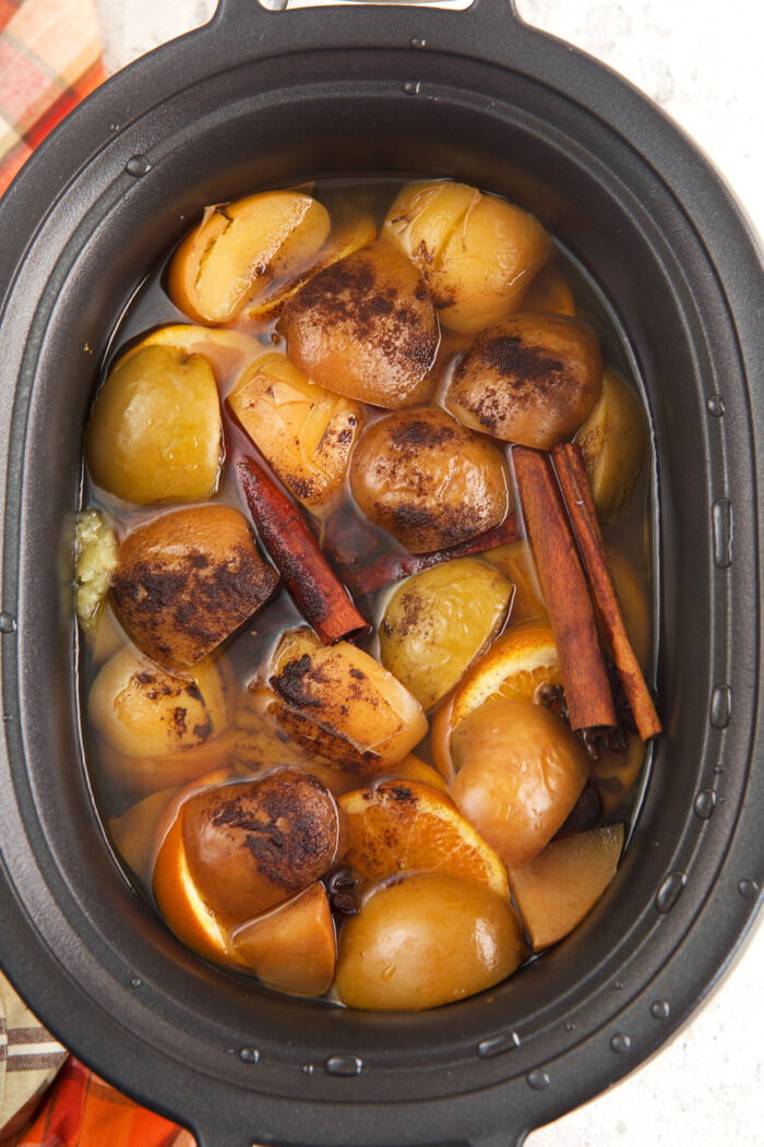 Crockpot with cooked apples, oranges, and spices for apple cider