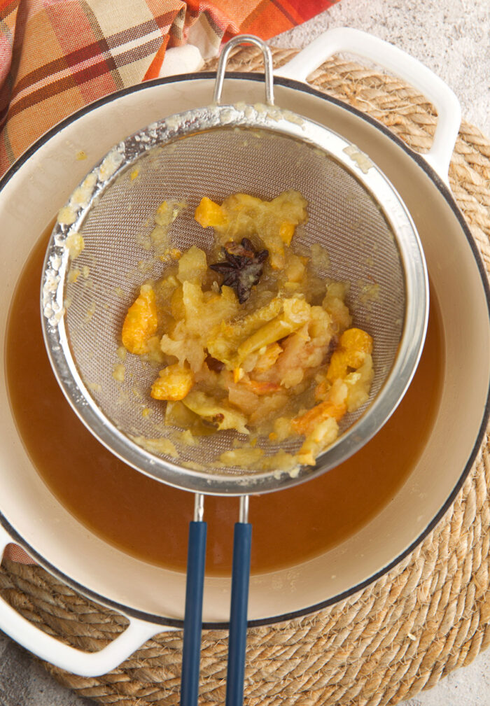 Straining apple cider into bowl