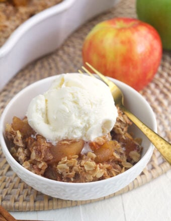 A scoop of vanilla ice cream is placed on top of a serving of apple crisp.
