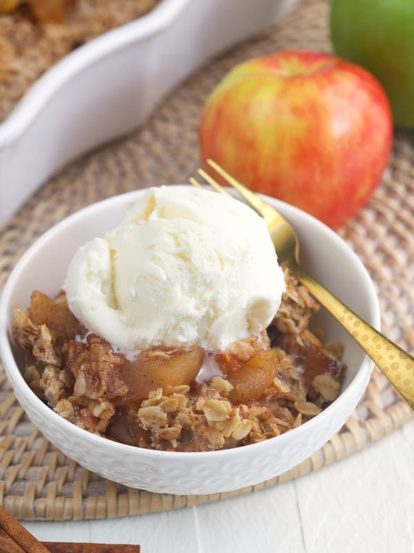 A scoop of vanilla ice cream is placed on top of a serving of apple crisp.