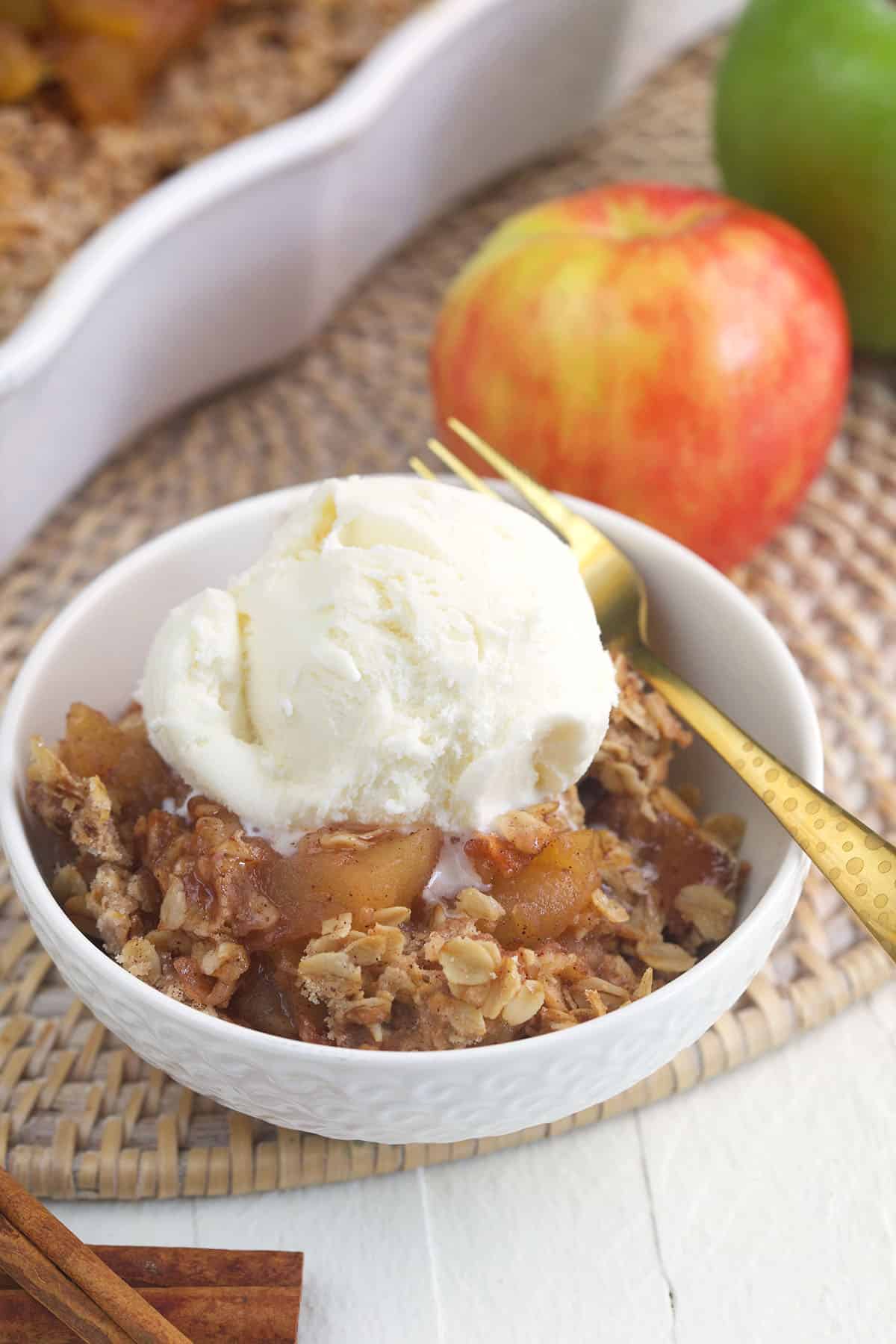 A scoop of vanilla ice cream is placed on top of a serving of apple crisp. 