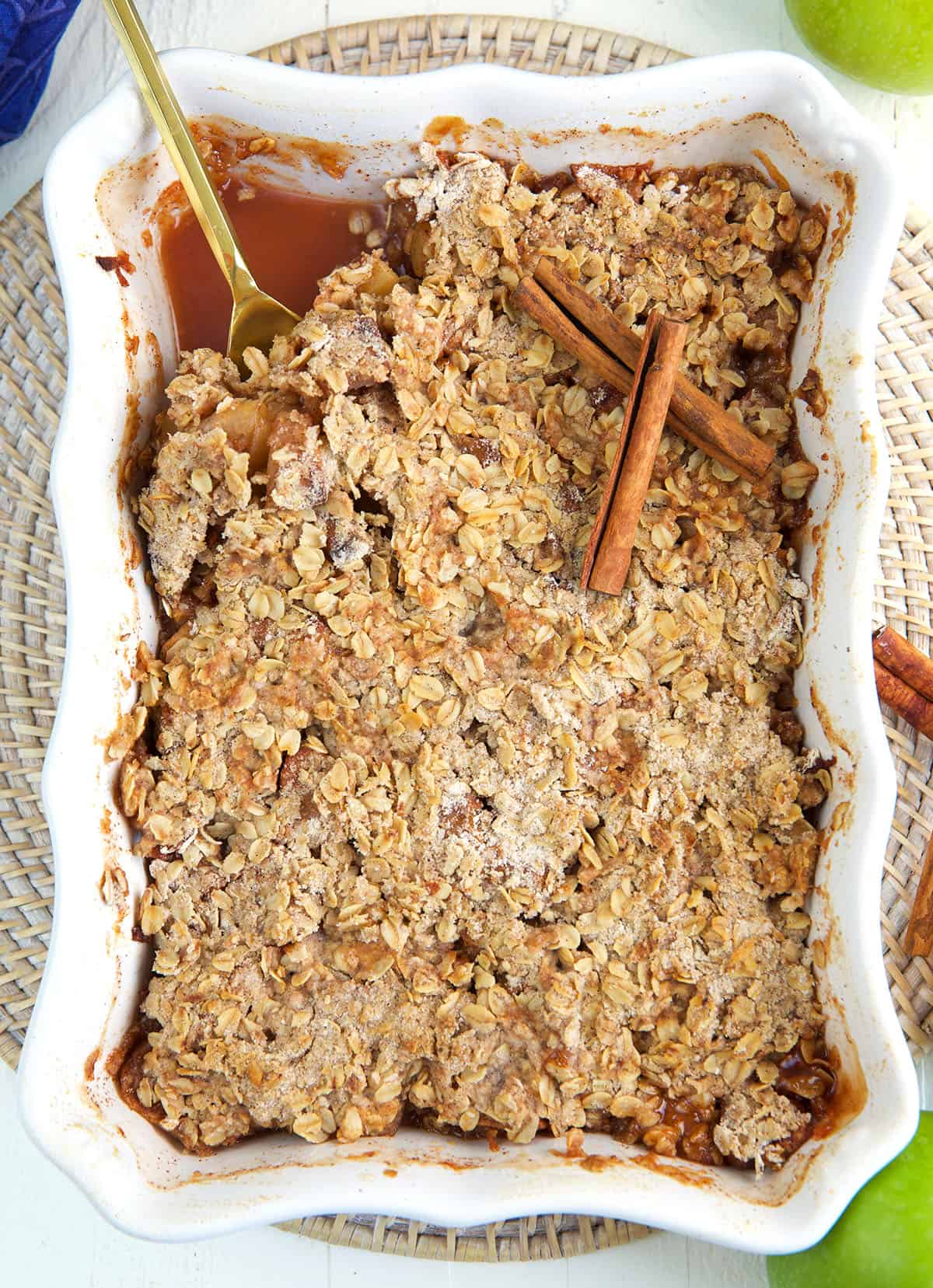 A serving spoon is placed in a dish filled with apple crisp. 