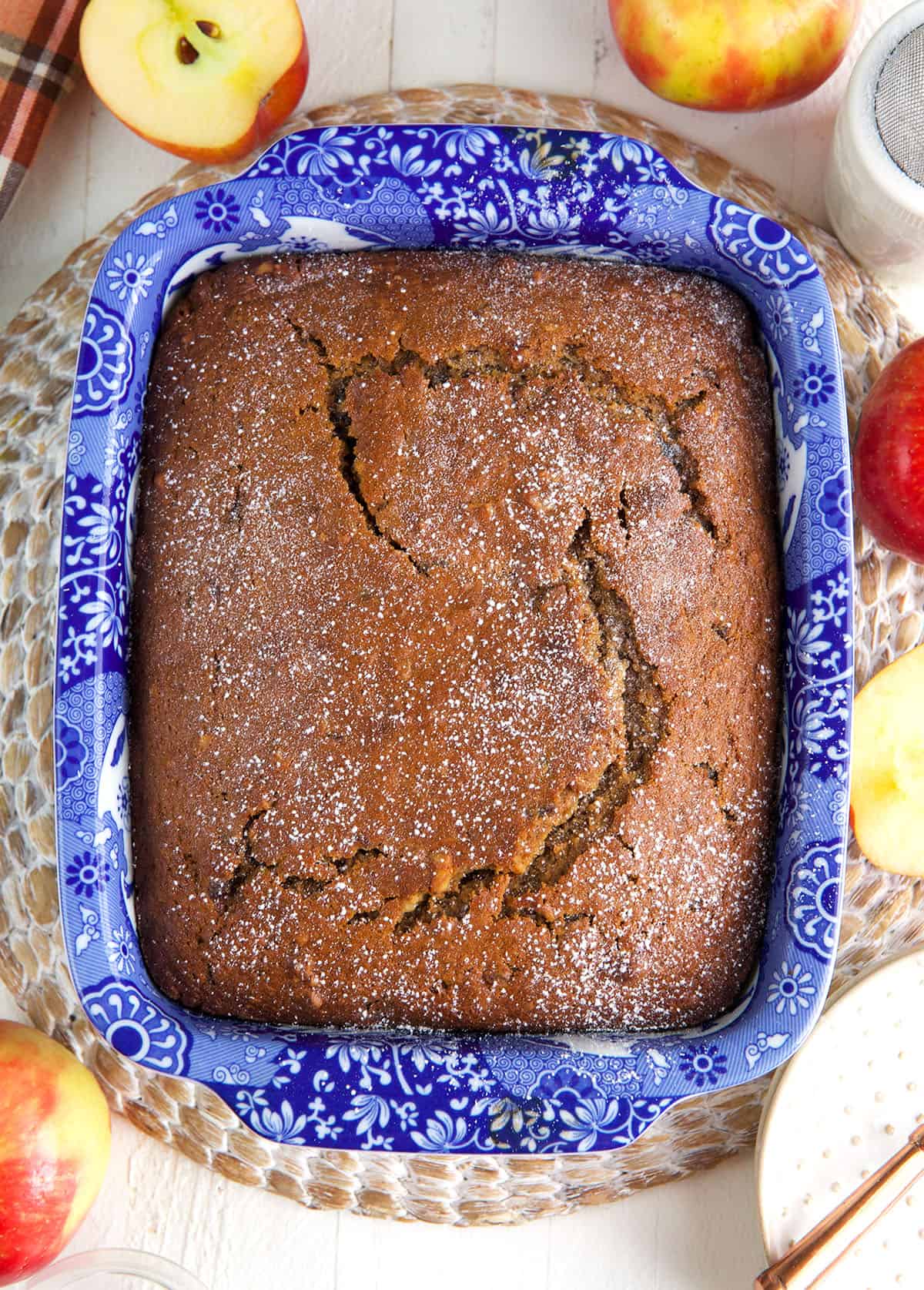 A baked applesauce cake is presented in a blue baking dish. 